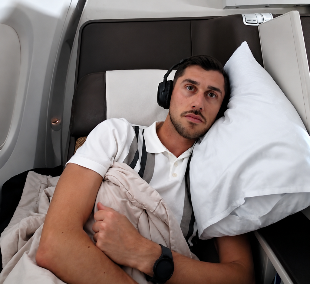 Blake Hatton reclined with blanket and pillow on the Oman Air Business Class B737
