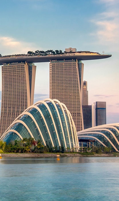 Singapore skyline featuring Marina Bay Sands with its boat-shaped rooftop and the glass-domed Gardens by the Bay along the waterfront.