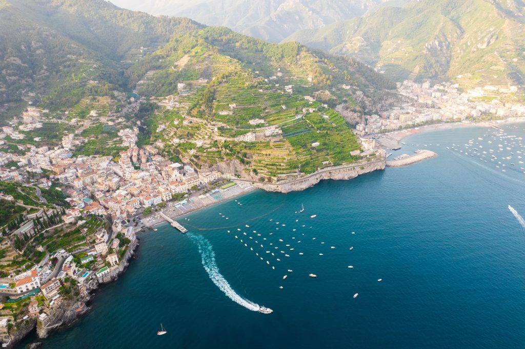 Aerial view of a seaside town built on terraced hillsides with boats in a harbor.